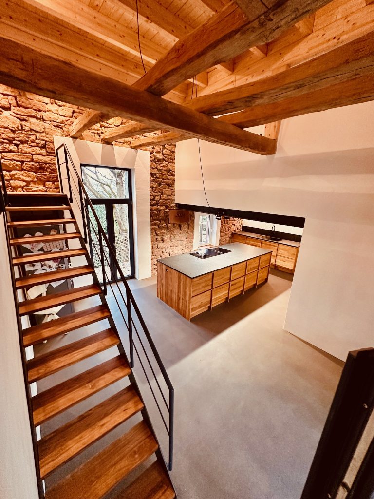Kücheblock in der Mitte des Raumes mit Kochfeld aus Eiche - links eine Treppe