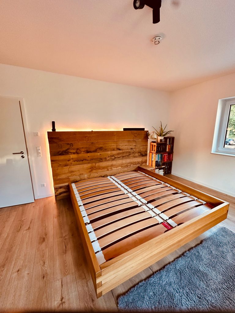 Bett aus Eiche mit Lattenrost auf eichenboden mit Teppich und weßer Tür Bett aus Eiche mit Lattenrost auf eichenboden mit Teppich und weßer Tür